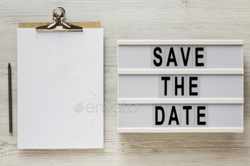 'Save the date' words on a lightbox, clipboard with blank sheet of paper