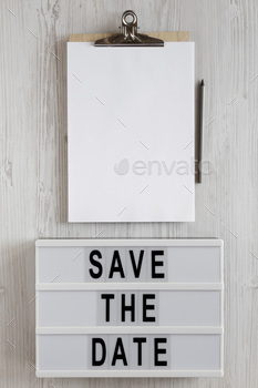 'Save the date' words on a lightbox, clipboard with blank sheet of paper