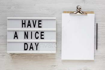 'Have a nice day' words on a lightbox, clipboard with blank sheet of paper