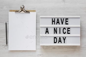 'Have a nice day' words on a lightbox, clipboard with blank sheet of paper