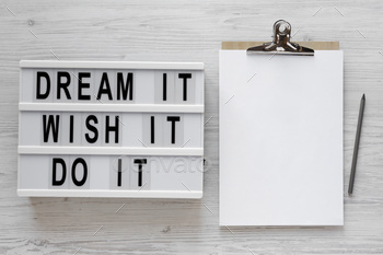 'Dream it, wish it, do it' words on a lightbox, clipboard with blank sheet of paper.