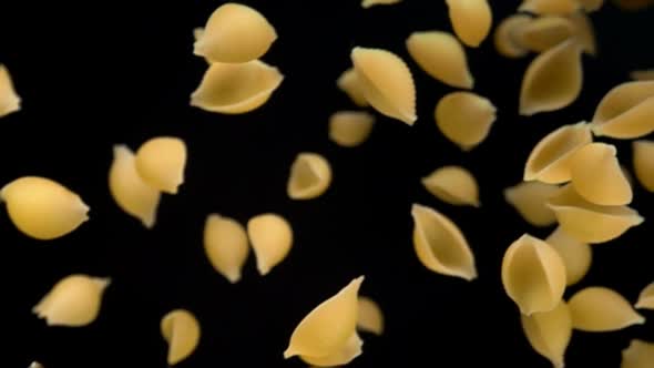 Pasta Conchiglie is Falling Diagonally on a Black Background