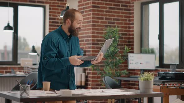 Employee Holding Laptop and Finding Good News About Business