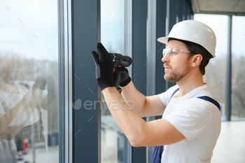service man installing window with screwdriver