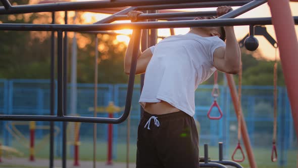 Young Middle Eastern Guy Doing Pullups Exercises During Workout at City Sports Ground Outdoors