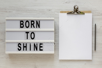 'Born to shine' words on a lightbox, clipboard with blank sheet of paper