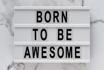 'Born to be awesome' words on a lightbox on a marble background, top view.