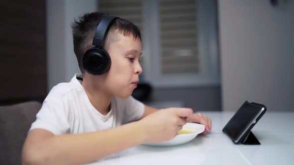 Cute Boy looking on a Tablet while Eating