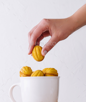 Hand placing a cookie on a cup filled with cookies