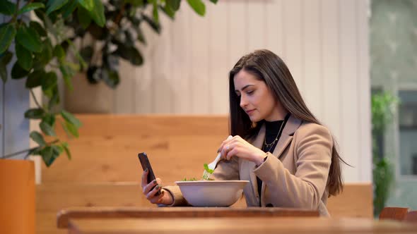 Video of Girl Eating a Salad and Using Cell Phone