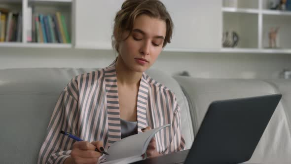 Millennial Student Making Notes Working on Laptop Computer at Home Closeup