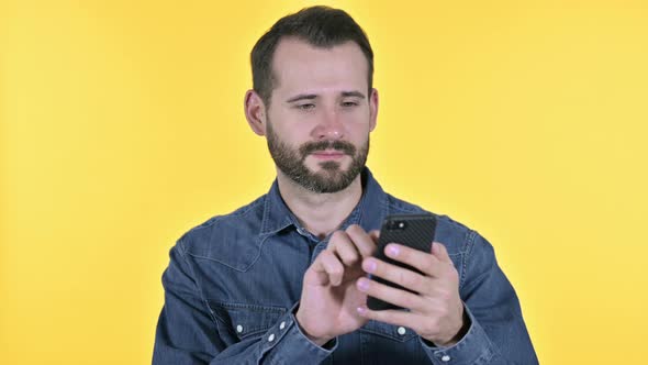 Beard Young Man Using Smartphone, Yellow Background