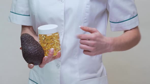 Nutritionist Doctor Holding Organic Avocado Fruit and Jar of Medicine or Vitamin or Omega 3 Capsules