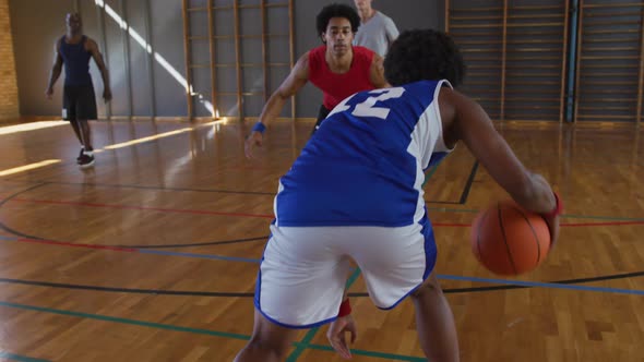 Diverse male basketball team and coach playing match