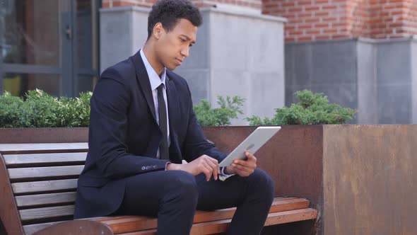 Designer Using Tablet Computer While Sitting on Bench