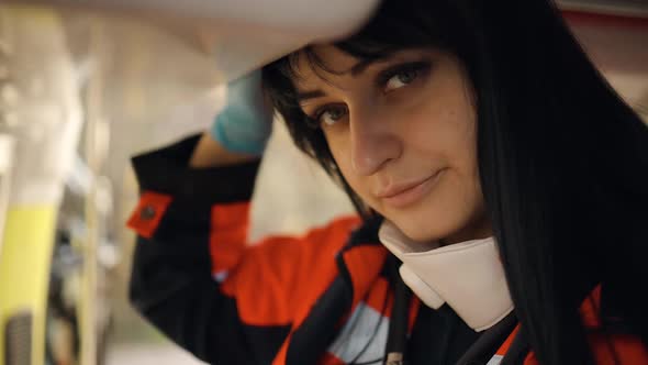 Smiling Tired Female Paramedic with Lowered Respirator Looks at you