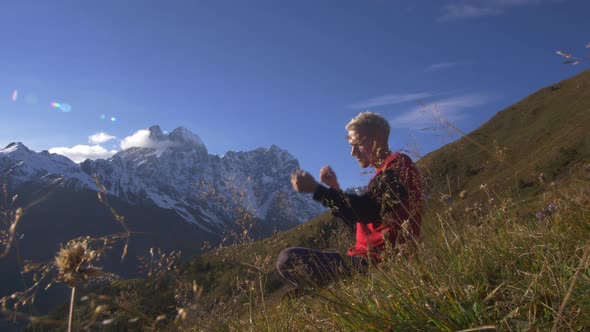 Male Tourist Athlete Sitting on a Rock in the Mountains and Looking at the Beauty of Nature