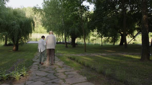 Young Nurse Helps Her Old Patient Walk in the Park