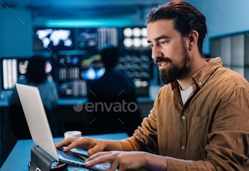 Young stock trader businessman working on laptop in dark office