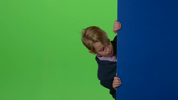 Teen Peeks Out From the Side the Boards and Shows Dislike on a Green Screen