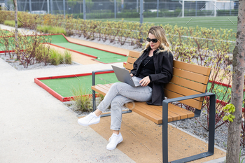 A businesswoman using a laptop on a golf course