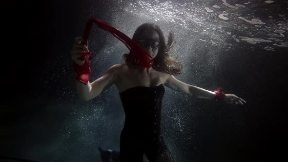 A Woman in a Black Suit Swims Under the Water