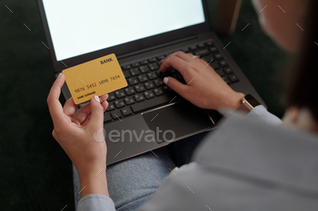Credit card held by woman with laptop