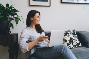 Happy woman using devices on sofa