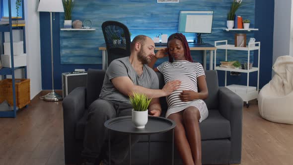 Interracial Couple Expecting Child and Bonding on Couch