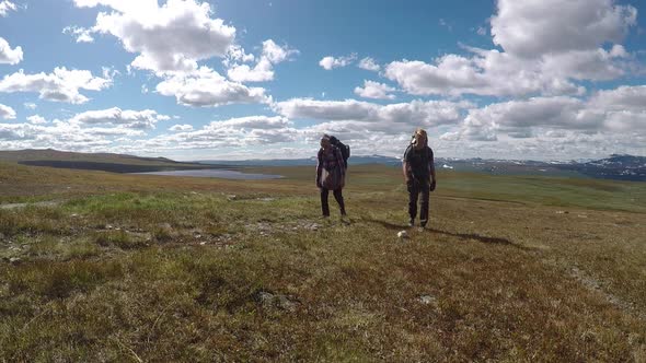 two happy hikers walking towards the camera in the mountains with a scenic background. blue skies an