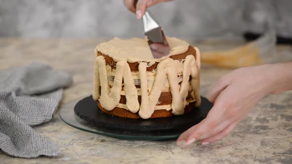 Girl Making a Cake in a Bakery. Baker Squeezes Cream Onto a Cake Layer.