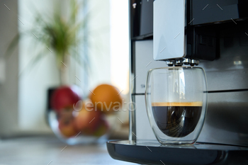 Coffee machine with cup of coffee in kitchen