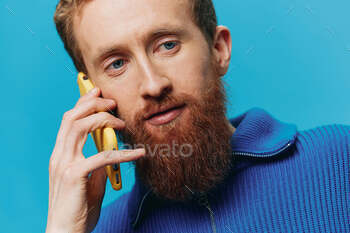 Portrait of a man with a phone in his hands does looking at it and talking on the phone, on a blue