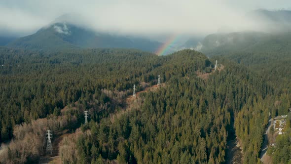 Aerial flying toward a rainbow in the stunning Mountain Forest around North Vancouver, British Colum