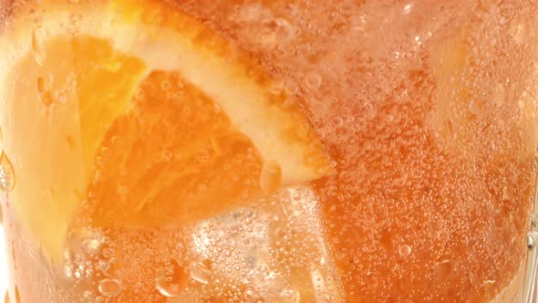 Pouring Mineral Carbonated Water Glass with Natural Orange Pieces Slow Motion Closeup Macro Shot