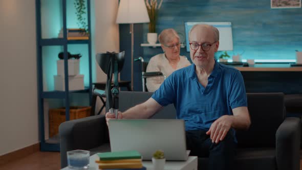 Senior Man Enjoying Online Video Call on Laptop with Family