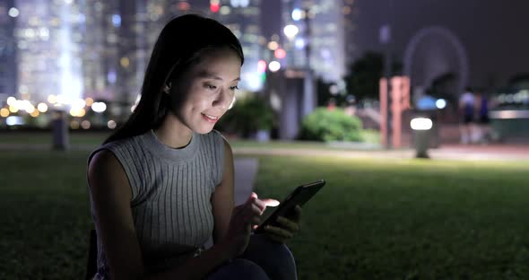 Woman using smart phone in city at night 