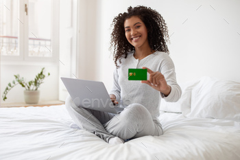 Woman Sitting on Bed With Laptop and Credit Card