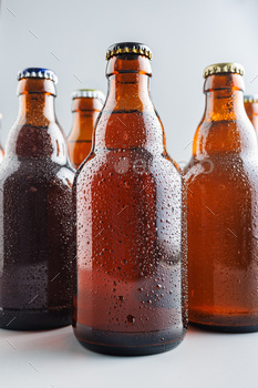 Beer bottle with drops on gray background.