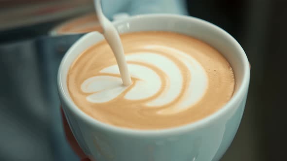 Barista making latte art in coffee shop. Professional man making pouring stream milk with espresso