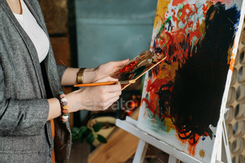 Woman artist creating canvas with paint in studio