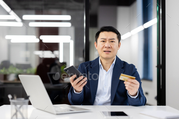 Businessman confused with two phones and a credit card