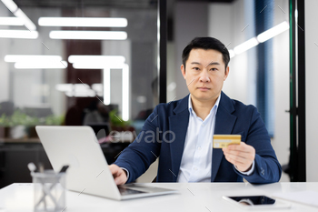 Businessman holding credit card at office desk