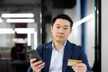 Businessman with credit card and smartphone in an office