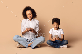 Woman and Child Sitting on Floor Looking at Cell Phone