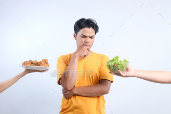 Confused Young Asian Male Choice Healthy Food Or Unhealthy Food