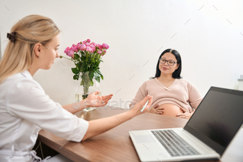 Young woman discussing terms and size of baby with pregnant woman