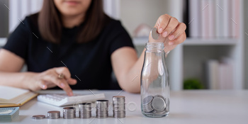 Woman saving money with hand putting coins in jug glass concept finance and accounting finance and