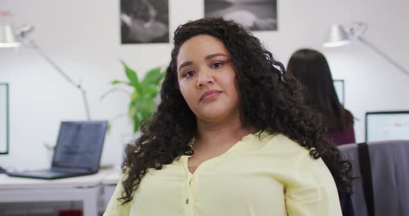 Portrait of smiling biracial businesswoman looking at camera in modern office