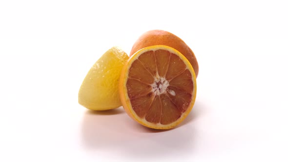 Fresh Cutted Red Oranges and Lemon are Spinning on White Background